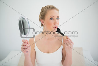 Natural blonde holding mirror and using brush