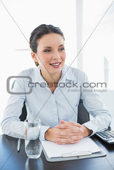 Stylish brunette businesswoman joining her hands and looking away