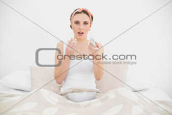 Surprised woman watching television eating popcorn