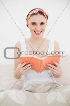 Young woman holding a book smiling into the camera