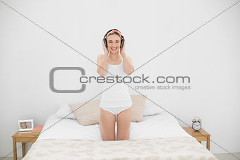 Smiling young woman listening to music in her bed