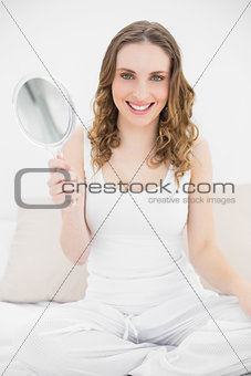 Young woman smiling into the camera and sitting on her bed