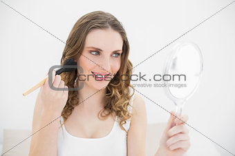 Smiling woman putting powder on her cheeks