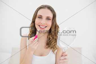 Smiling woman using lip gloss