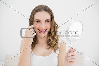 Pretty woman plucking her eyebrows while smiling into the camera