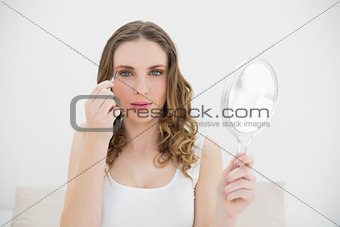 Pretty woman plucking her eyebrows while looking into the camera
