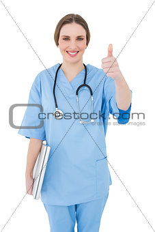 Young female doctor holding a white notebook and putting thumbs up