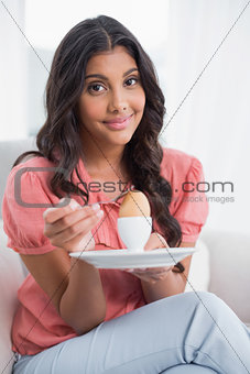 Content cute brunette sitting on couch holding hard boiled egg