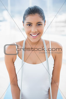 Gleeful toned brunette sitting on floor with skipping rope