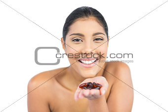 Cheerful nude brunette holding tablets in open hand