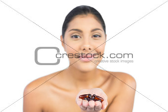 Happy nude brunette holding tablets in open hand
