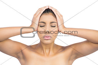 Serious nude brunette holding her head with closed eyes
