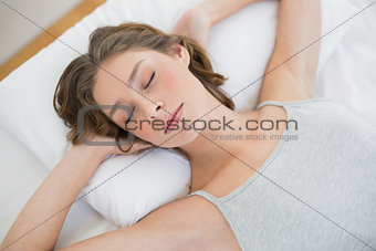 Peacefully sleeping woman lying on her white bed