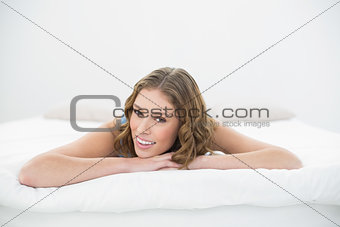 Beautiful young woman lying on her bed on her belly