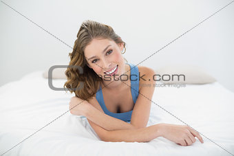 Beautiful smiling woman smiling cheerfully at camera while lying on her bed