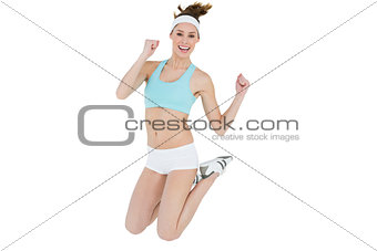 Sporty young woman jumping smiling cheerfully at camera