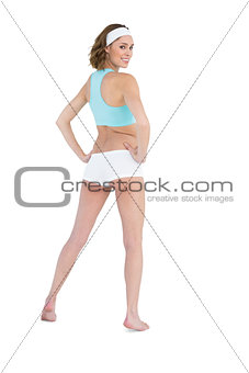 Pretty slender woman looking over her shoulder at camera wearing sportswear