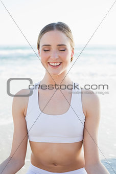 Happy slender woman sitting on the beach peacefully