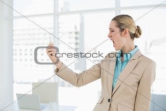 Attractive young businesswoman looking shocked at her smartphone