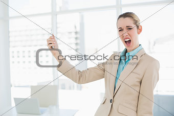 Cute shocked businesswoman holding her smartphone looking at camera