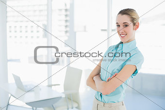 Beautiful young businesswoman posing with arms crossed in her office