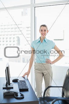 Happy beautiful businesswoman posing in her office with hand on hip