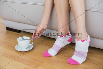 Young slender woman wearing pink socks sitting on couch