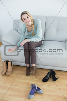 Gorgeous smiling woman tying her shoelaces sitting on couch