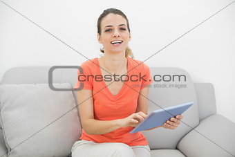 Amused casual woman using her tablet smiling cheerfully at camera