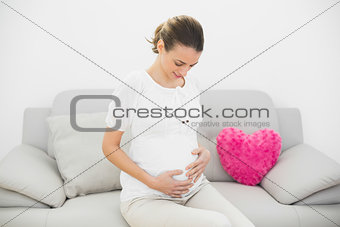Gorgeous pregnant woman touching her belly looking proudly at it