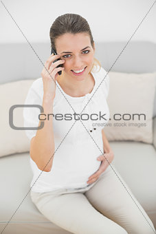 Lovely pregnant woman phoning with smartphone holding her belly