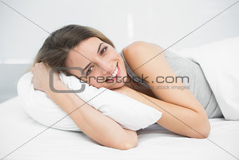 Happy brunette woman lying on her bed in the bedroom