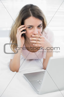Young woman phoning with smartphone lying on her bed
