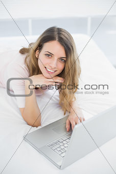 Gleeful woman using her notebook smiling cheerfully at camera