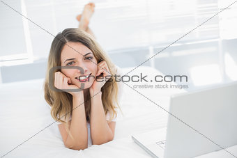 Woman lying on her bed smiling cheerfully at camera