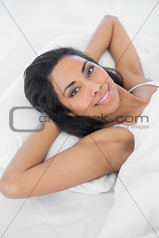 Content woman lying on her bed smiling cheerfully at camera