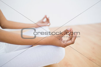 Mid section of slim young woman meditating sitting in lotus position