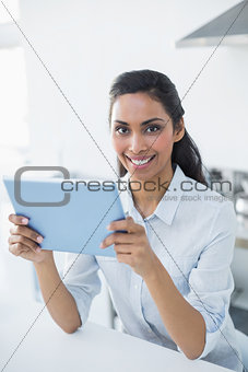 Attractive peaceful woman holding her tablet smiling cheerfully at camera