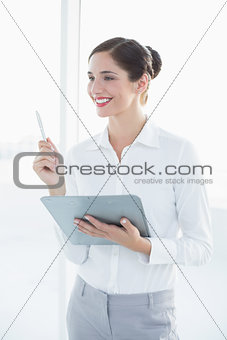 Smiling young business woman with clipboard and pen