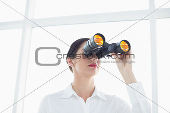 Business woman  looking through binoculars in office