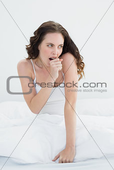 Woman sitting and yawning in bed