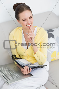 Thoughtful woman with personal organizer and laptop