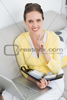 Smiling woman with personal organizer and laptop