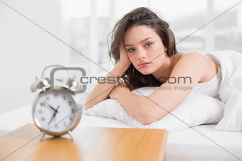 Beautiful woman in bed with alarm clock on bedside table