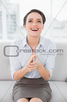 Smiling well dressed woman applauding while looking up