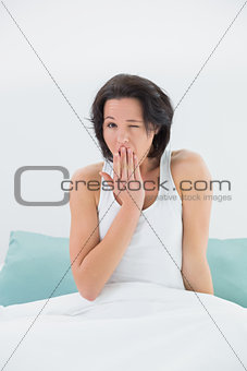 Portrait of a young woman yawning in bed