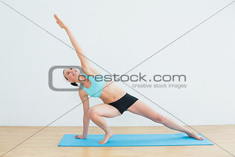 Slim woman doing the side plank yoga pose