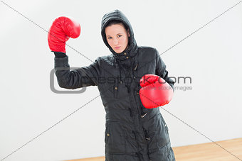 Tought woman in hooded jacket and red boxing gloves