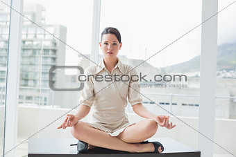 Smart businesswoman sitting in lotus position at office