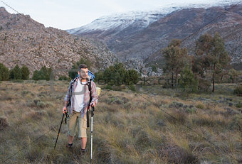 Man with backpack and trekking poles walking on landscape